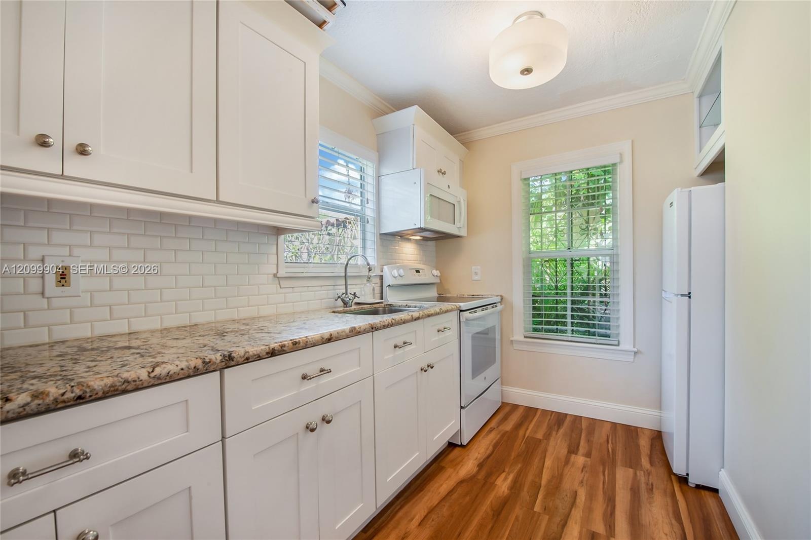 Kitchen featuring white shaker-style cabinetry, stone-patterned countertops, white subway tile backsplash, wood-finish flooring, and a flush-mount cei