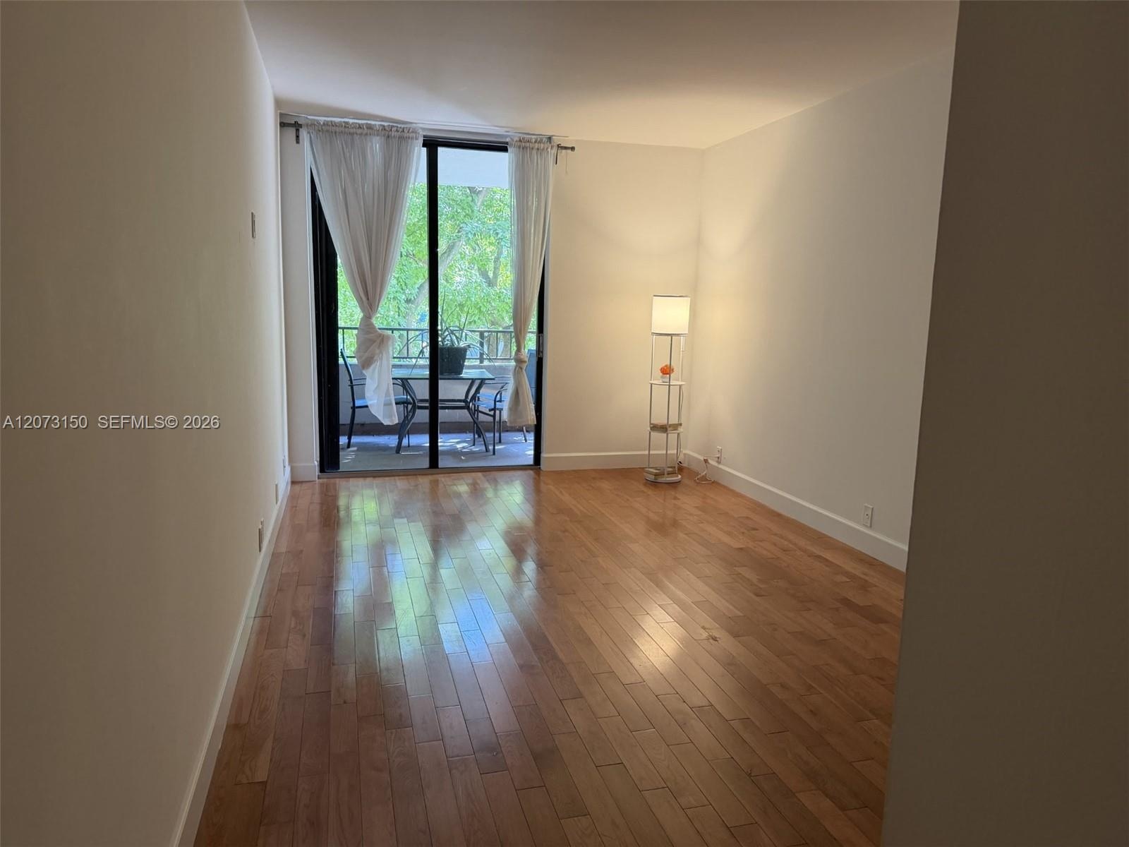 Living area featuring wood-finish flooring and floor-to-ceiling sliding glass doors providing access to a private balcony
