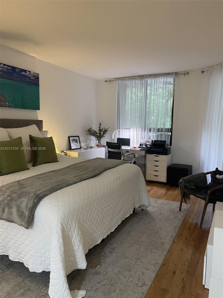 Hardwood flooring and floor-to-ceiling windows featuring metal curtain rods and sheer drapery