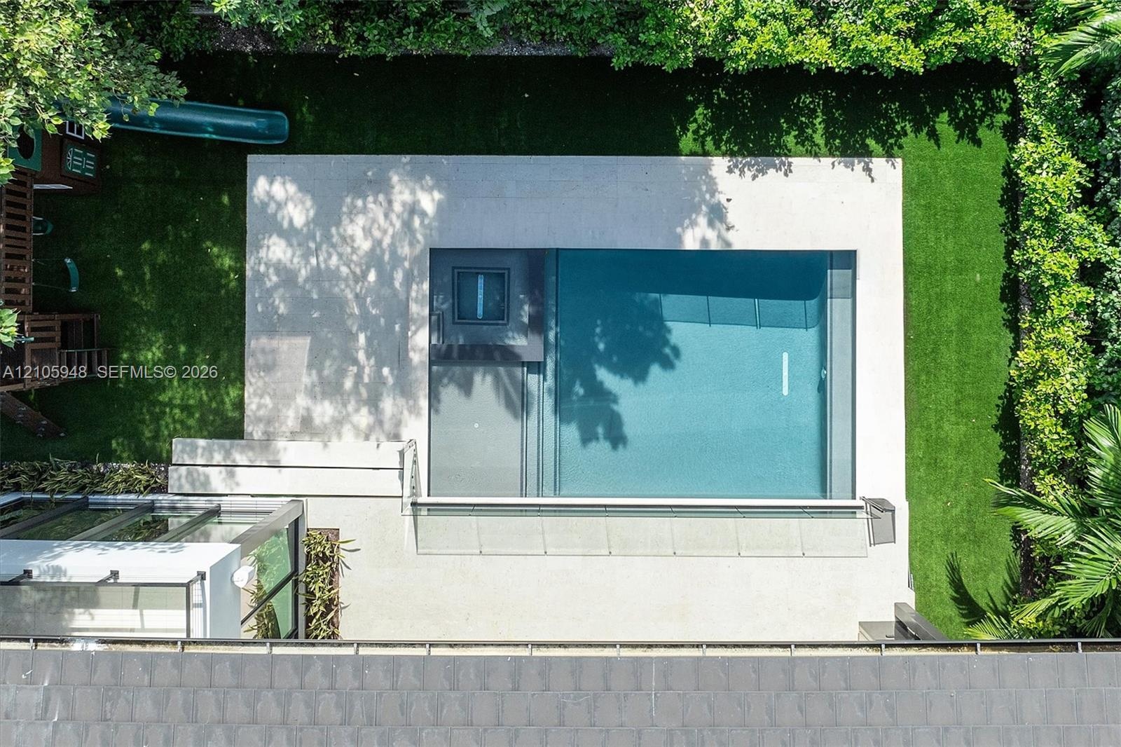 Modern residence featuring a clean-lined architectural facade with expansive glass panels, rendered white exterior walls, and manicured green lawn bor