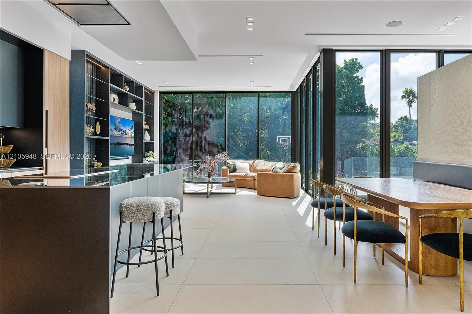 Open-concept interior featuring floor-to-ceiling glass walls, large-format tile flooring, recessed ceiling lighting, and custom built-in shelving