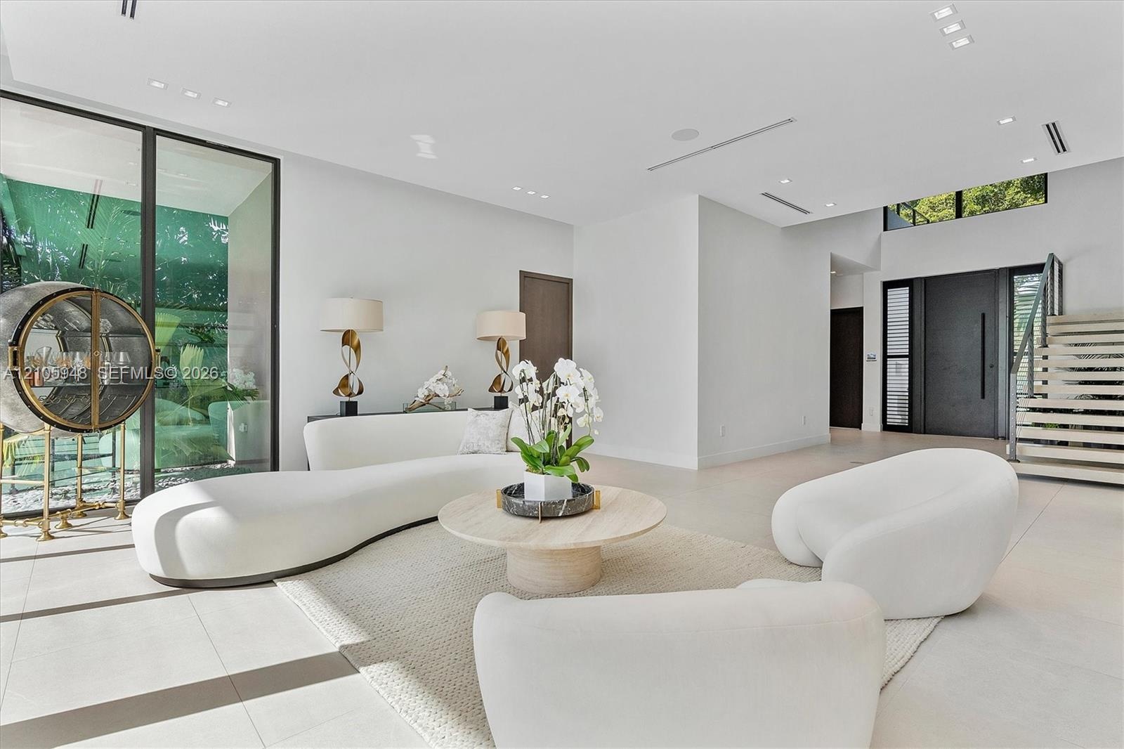 Open-concept living space featuring large-format tile flooring, floor-to-ceiling glass panel walls, recessed ceiling lighting, and a staircase with op