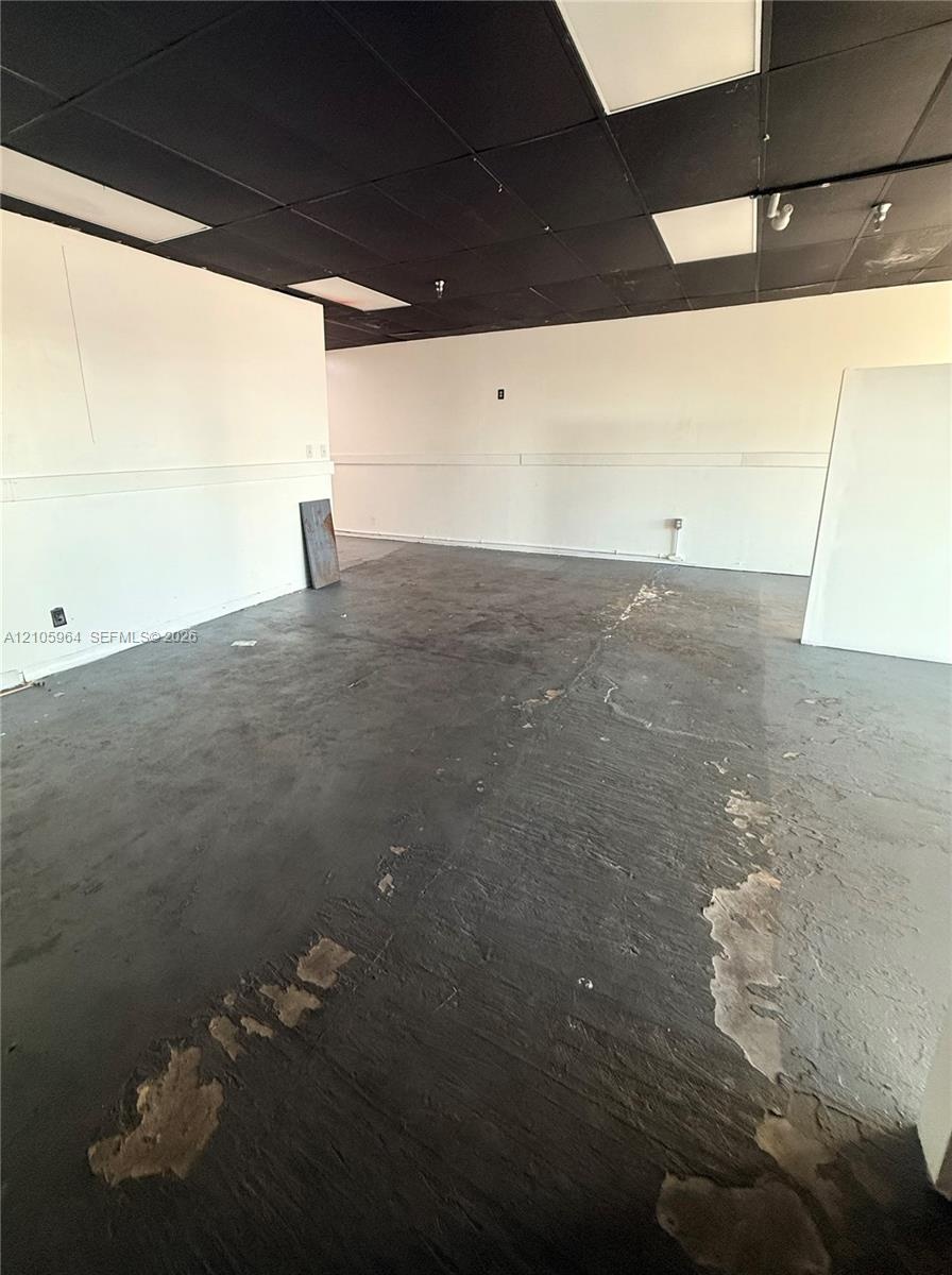 Open-concept interior featuring painted walls, a dark-toned drop ceiling with inset lighting, and exposed concrete flooring