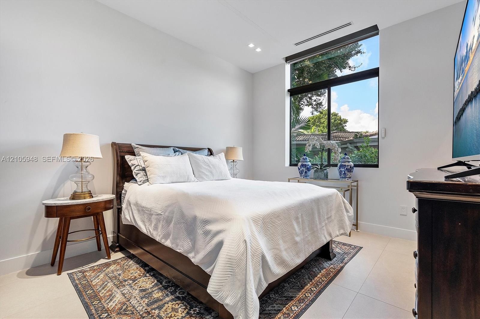 Neutral-toned room featuring large-format tile flooring, recessed ceiling lighting, and an oversized window with black trim
