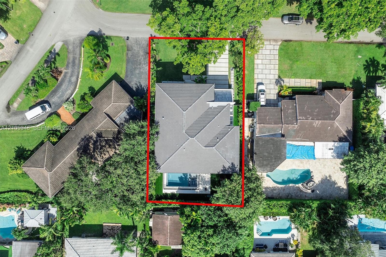 Aerial view of residential property featuring a hip roof, private swimming pool, paver driveway, and mature landscaping