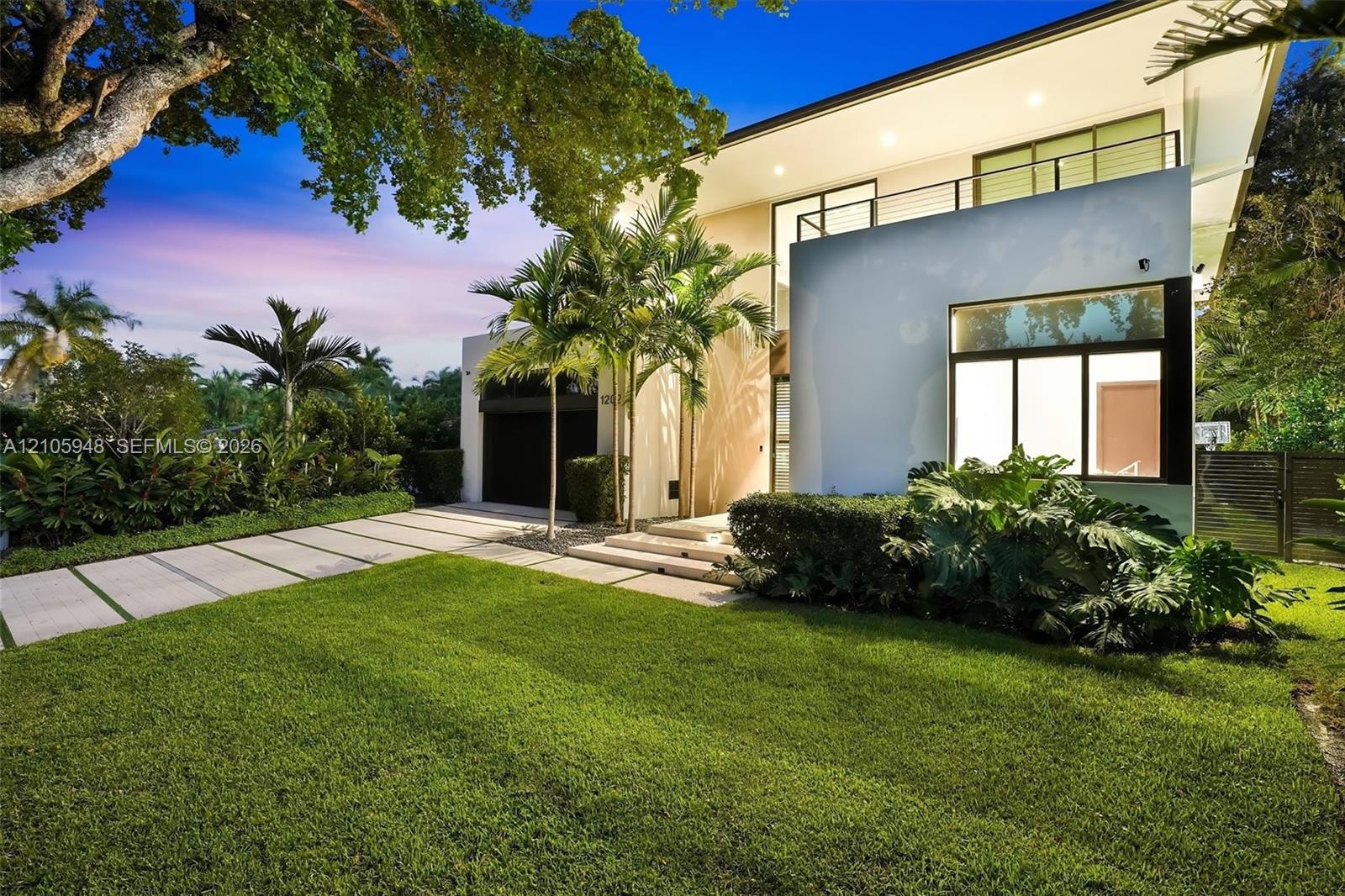 Modern two-story architectural exterior featuring smooth stucco finish, expansive glass windows, an upper-level balcony with metal railing, and a conc
