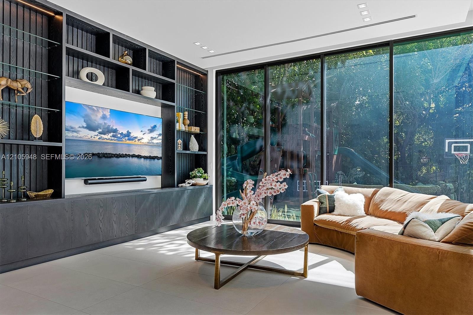 Custom dark-toned, floor-to-ceiling built-in cabinetry featuring integrated shelving, floor-to-ceiling glass walls, large-format tile flooring, and re