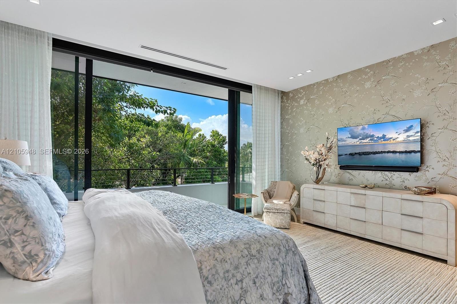 Floor-to-ceiling sliding glass doors, metal balcony railing, recessed ceiling lighting, and decorative wall covering