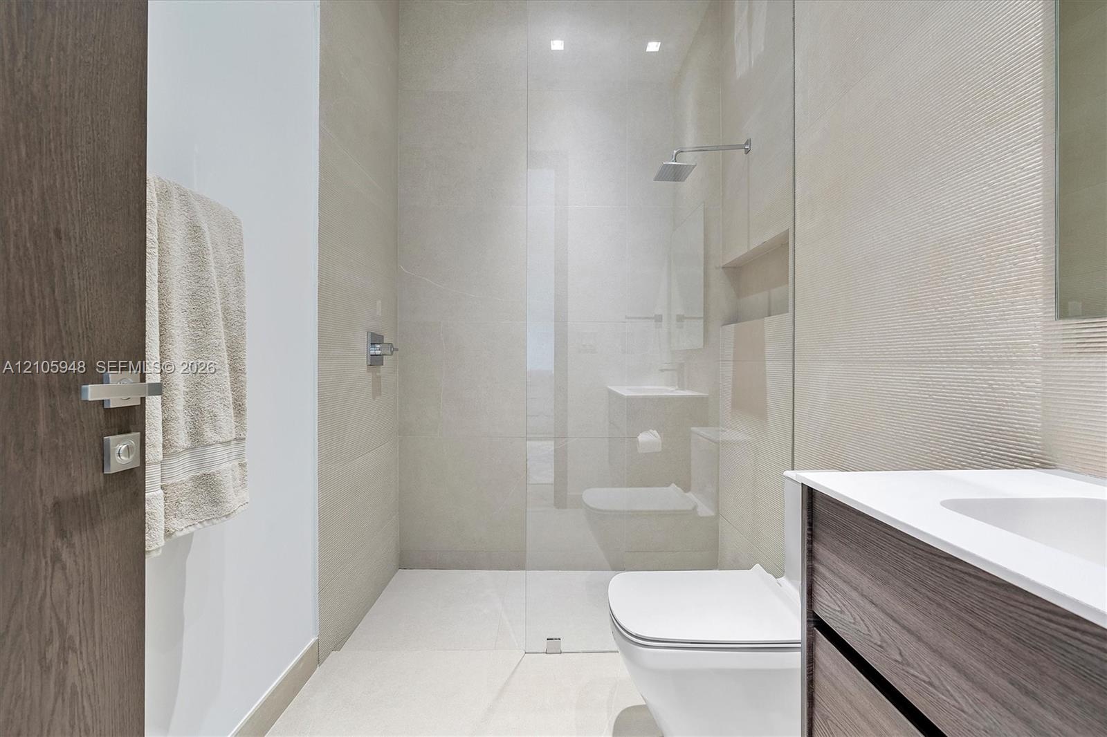 Walk-in shower with a glass enclosure, rain-style shower head, and recessed wall niche