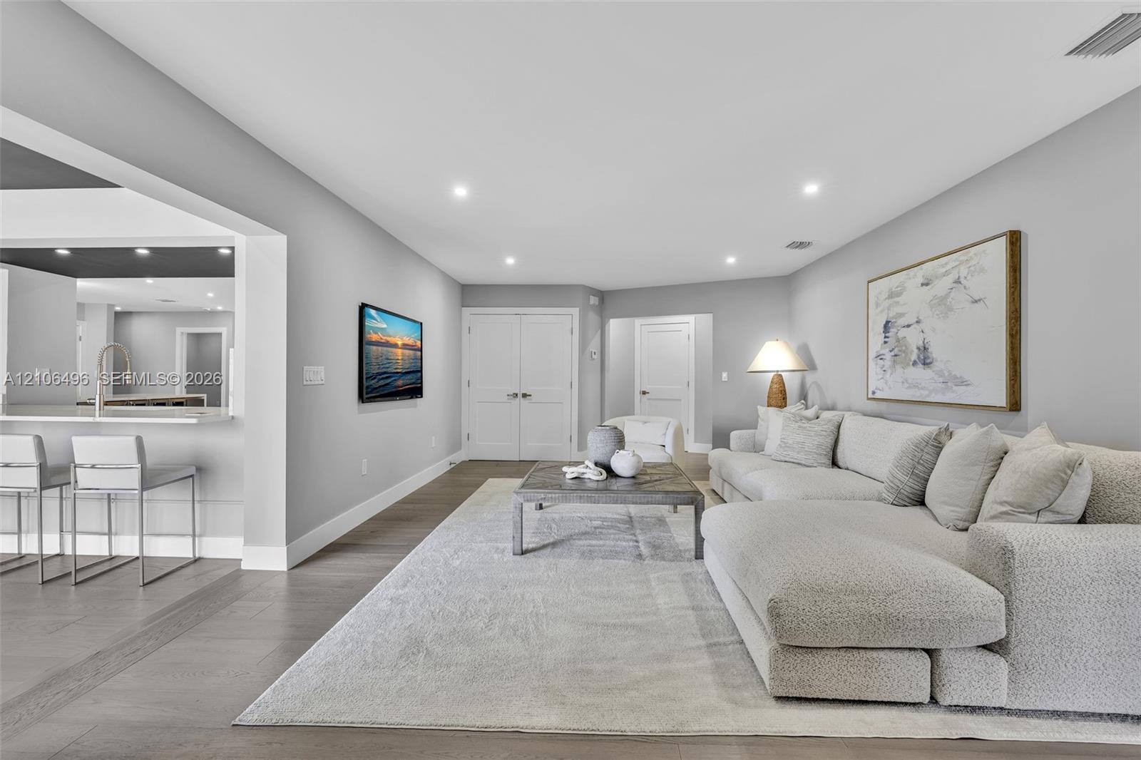 Open floor plan featuring wood-finish flooring, recessed lighting, and a breakfast bar with stone countertop