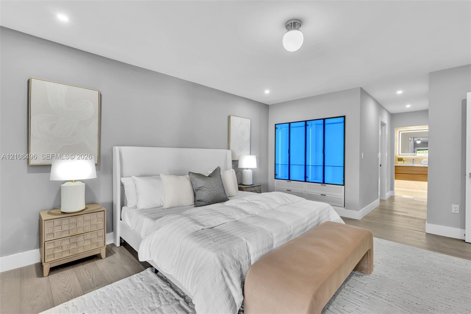 Neutral wall tones, wood-finish flooring, recessed lighting, and built-in glass-paneled cabinetry