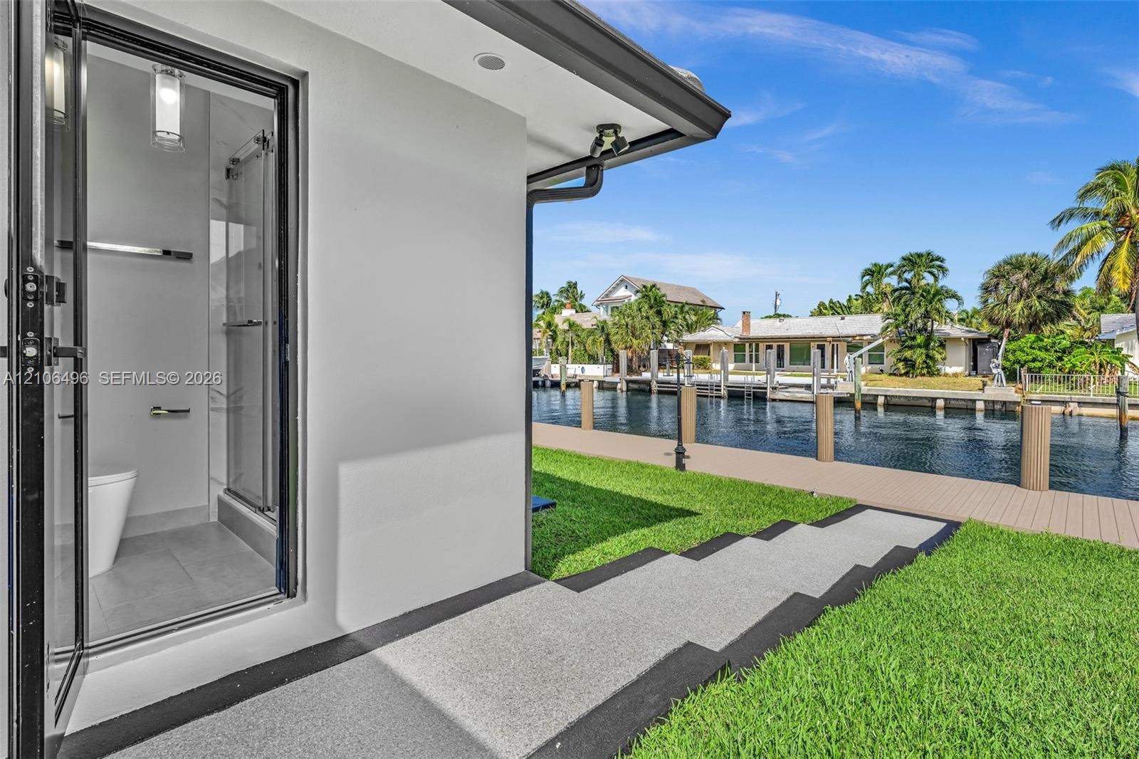 Exterior bathroom featuring a glass-enclosed shower, neutral-toned flooring, and modern fixtures, complemented by a composite dock, a concrete walkway