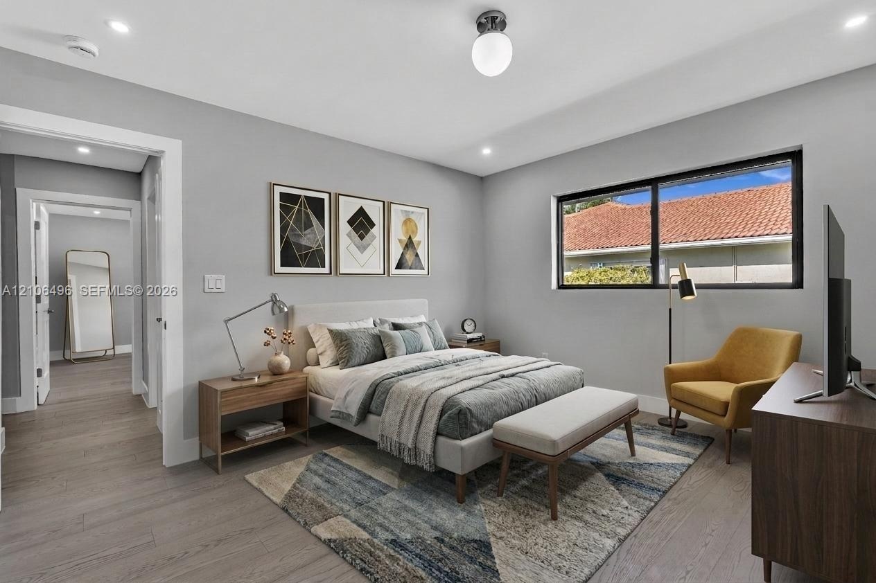 Neutral-toned interior featuring wood-finish flooring, recessed lighting, a modern spherical ceiling fixture, and a large horizontal window with a bla