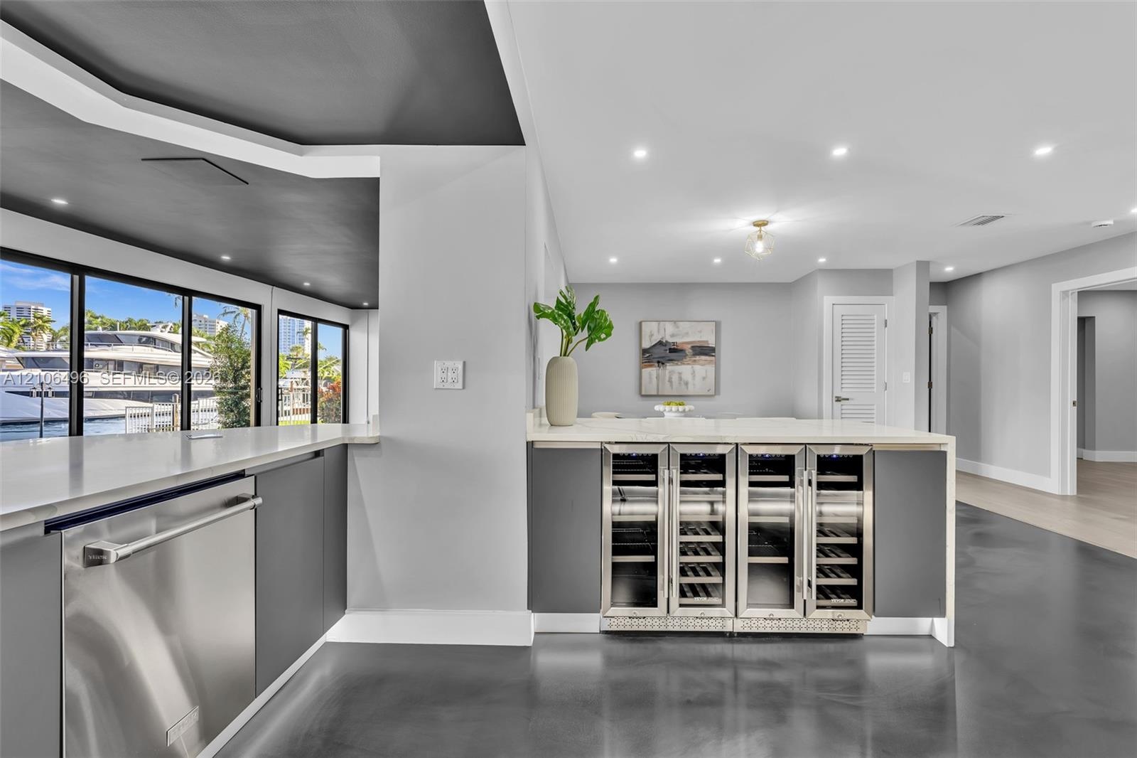 Wet bar featuring integrated stainless steel under-counter wine refrigerators, solid-surface countertops, recessed lighting, and large-format floor ti
