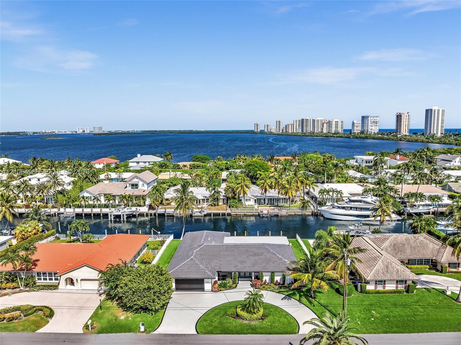 Waterfront property featuring a private boat dock, concrete seawall, circular driveway, and mature landscaping