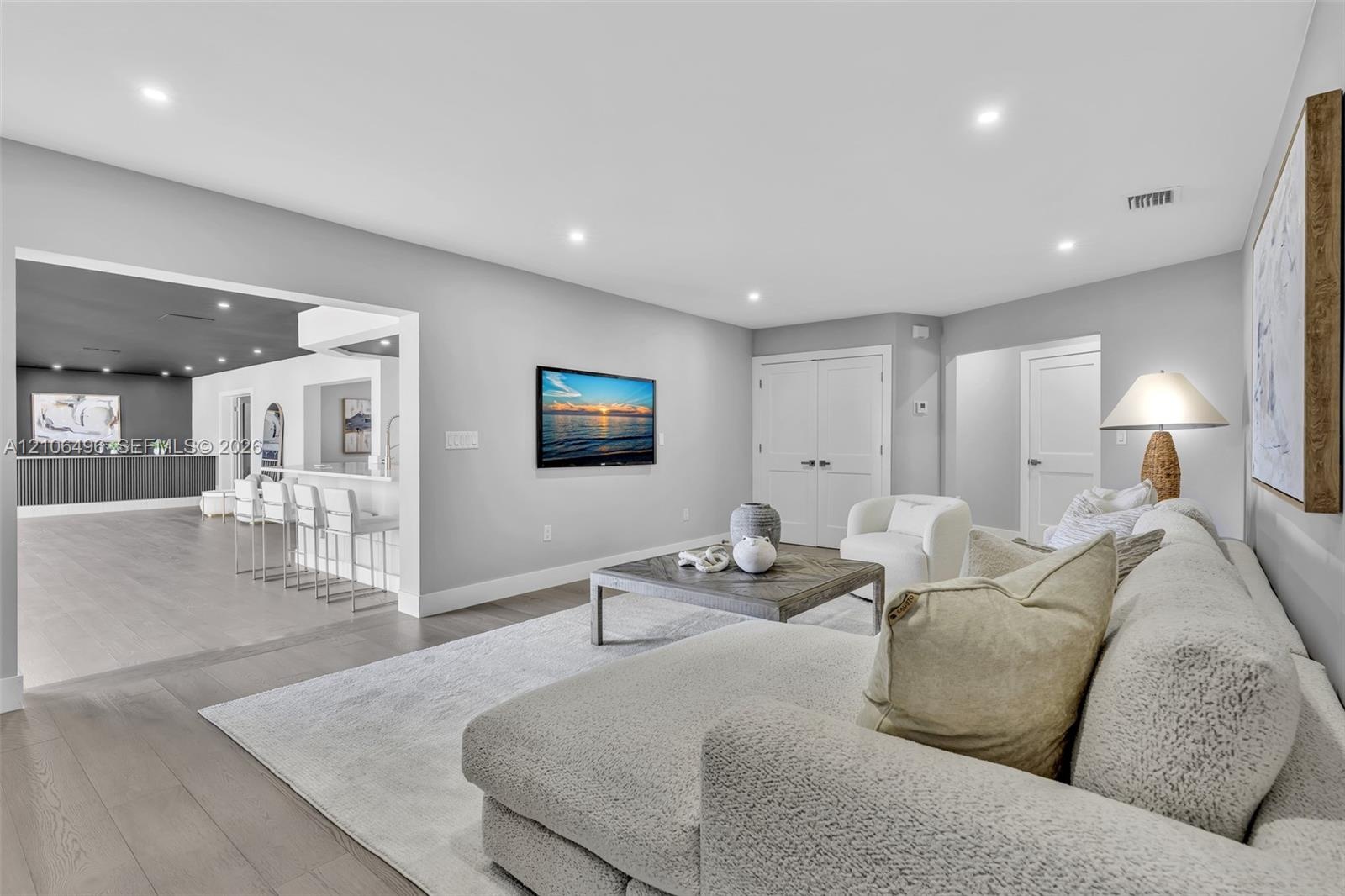 Neutral-toned living space featuring wood-finish flooring, recessed lighting, and double-door closet storage