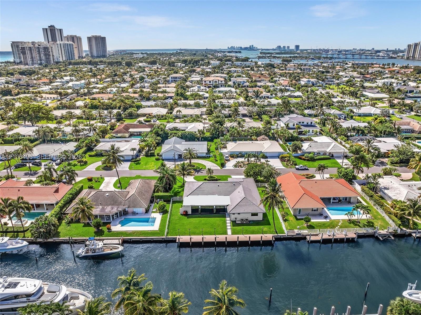 Waterfront property featuring a private bulkhead, deep-water access, expansive lawn, and mature palm trees