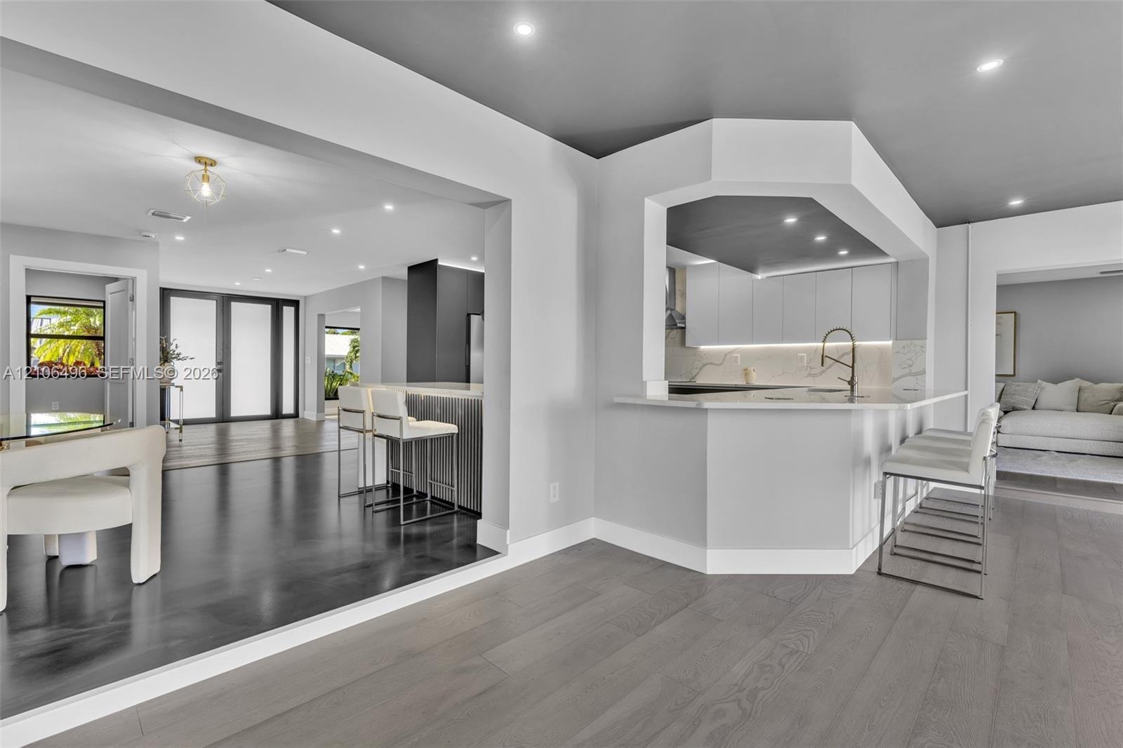 Open-concept kitchen featuring flat-panel cabinetry, a peninsula with stone-finish countertops, recessed lighting, and wood-finish flooring
