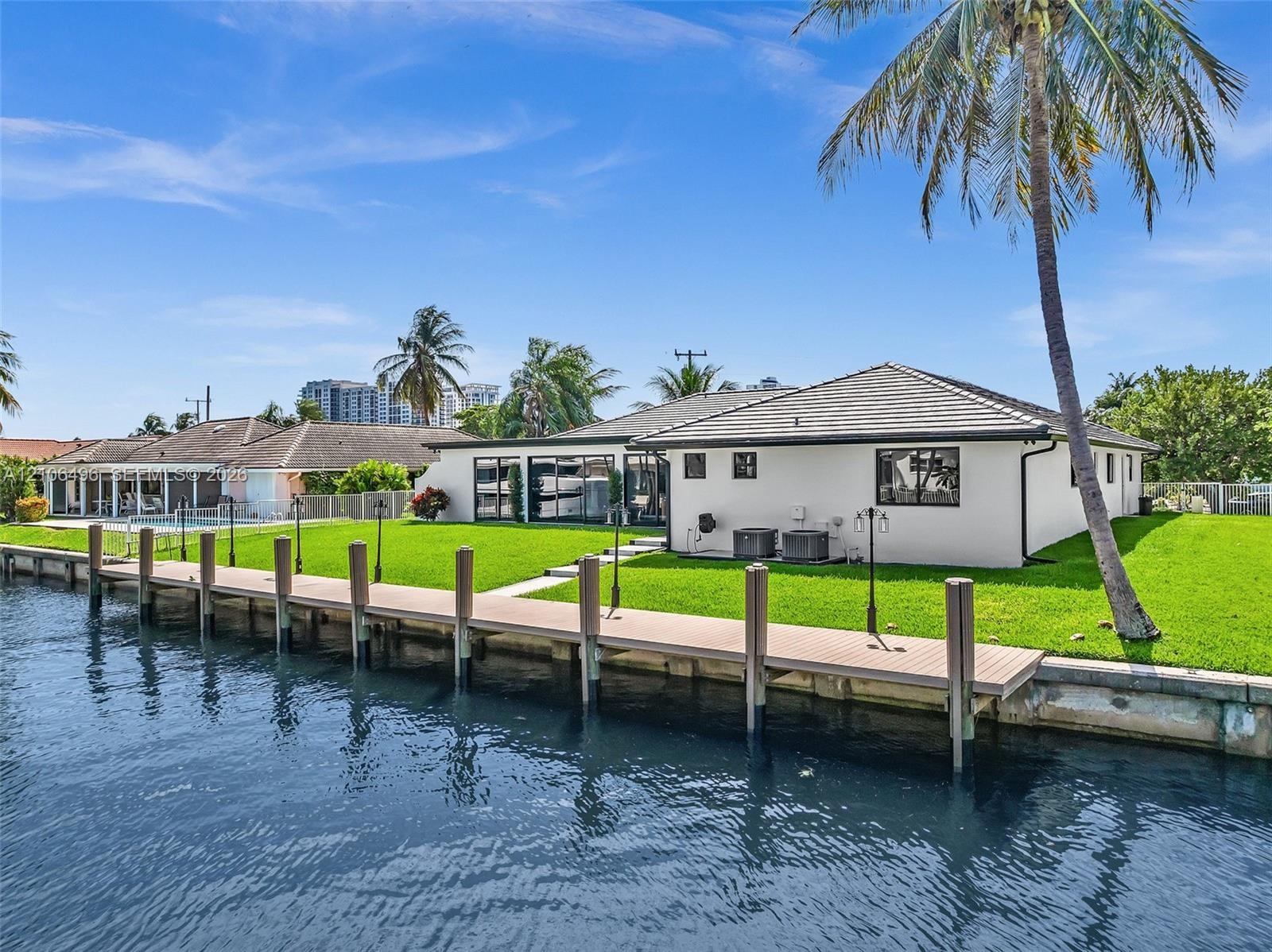 Waterfront exterior featuring a private dock, manicured lawn, and exterior lighting