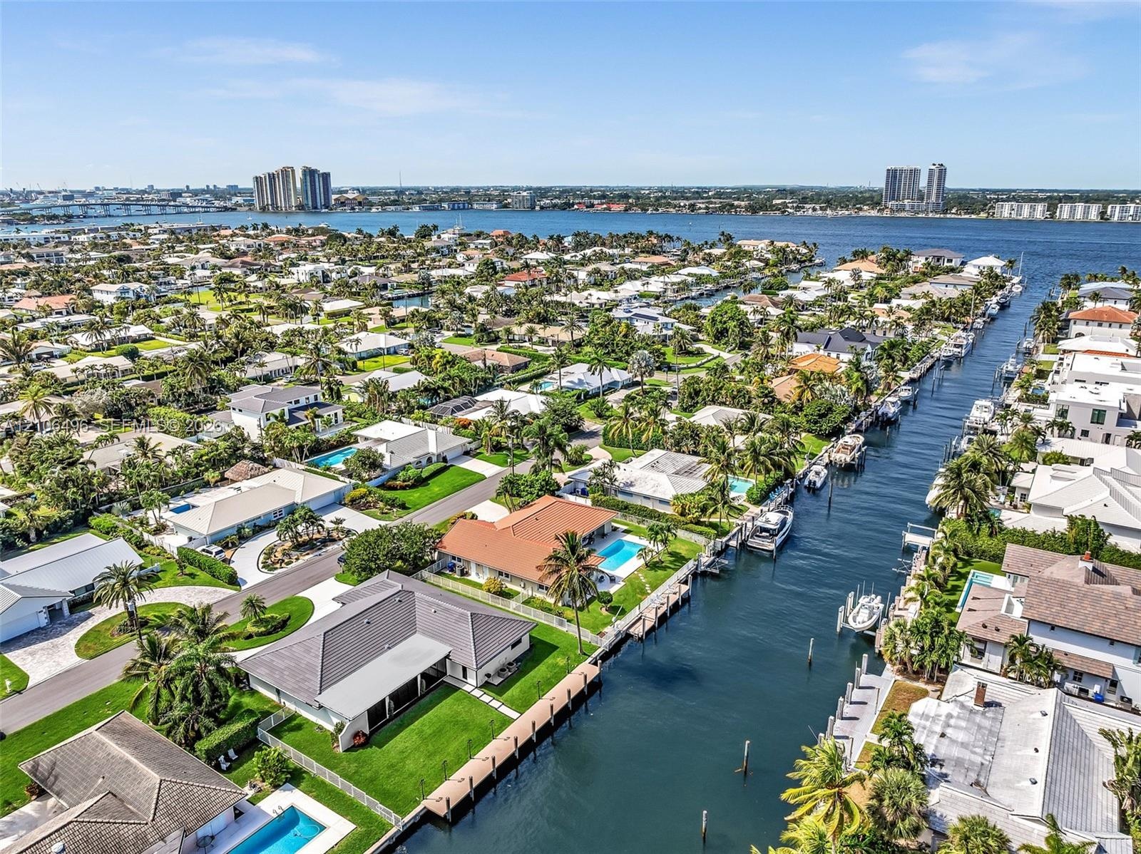 Waterfront property featuring direct canal access, a private dock, a swimming pool, and manicured landscaping