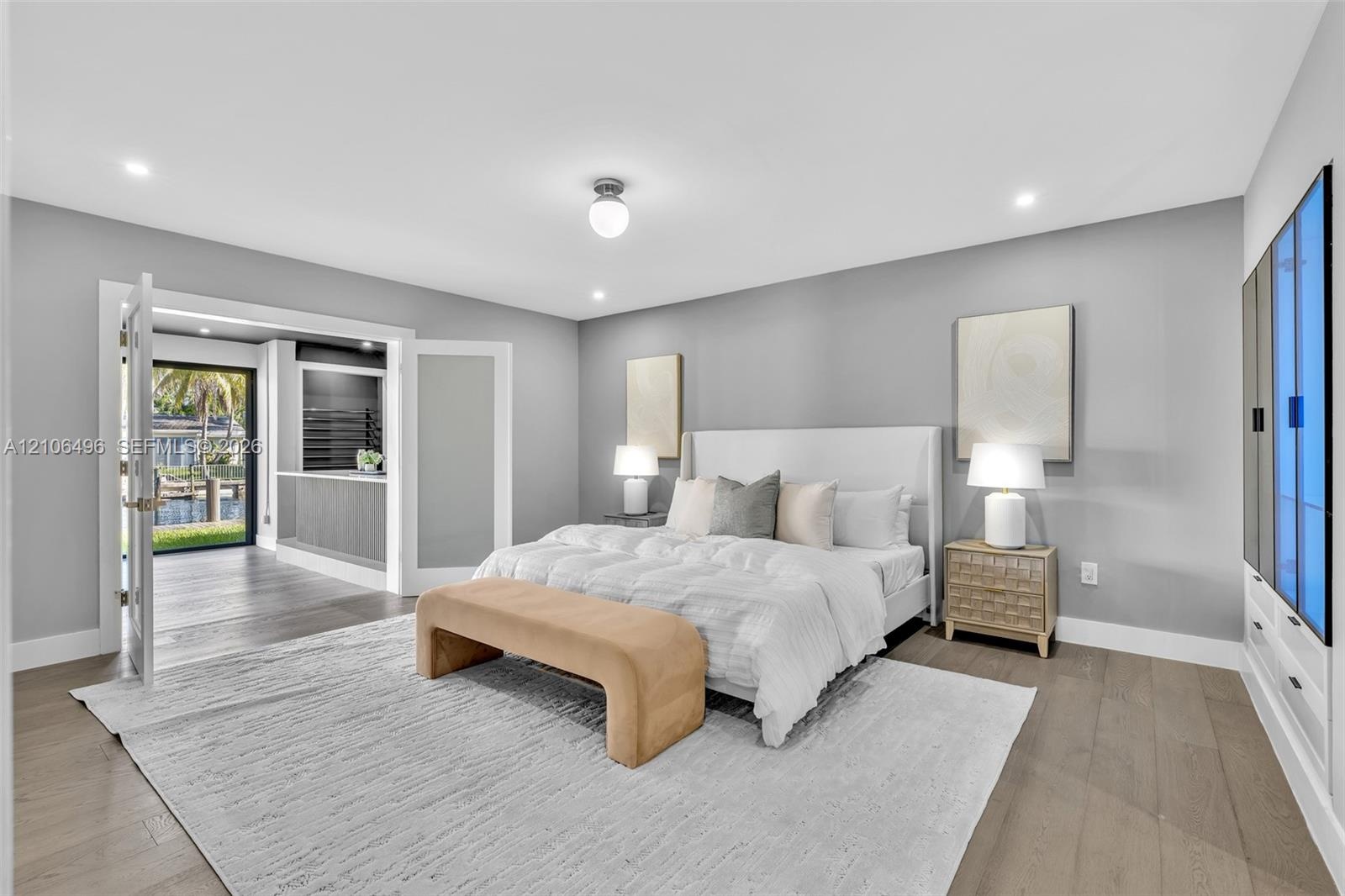 Interior space featuring wood-finish flooring, recessed lighting, built-in cabinetry with glass-front accents, and double glass-paneled doors opening 