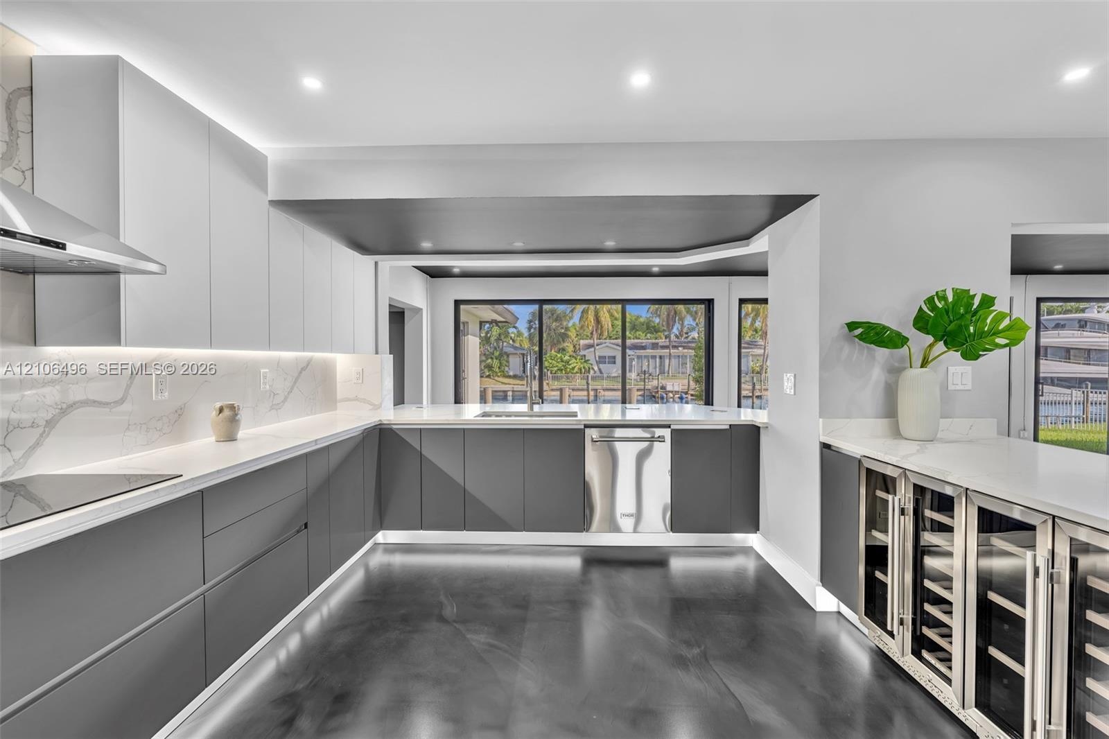 Kitchen featuring flat-panel cabinetry, light-toned stone-finish backsplash, built-in stainless steel appliances, polished flooring, and dual glass-do