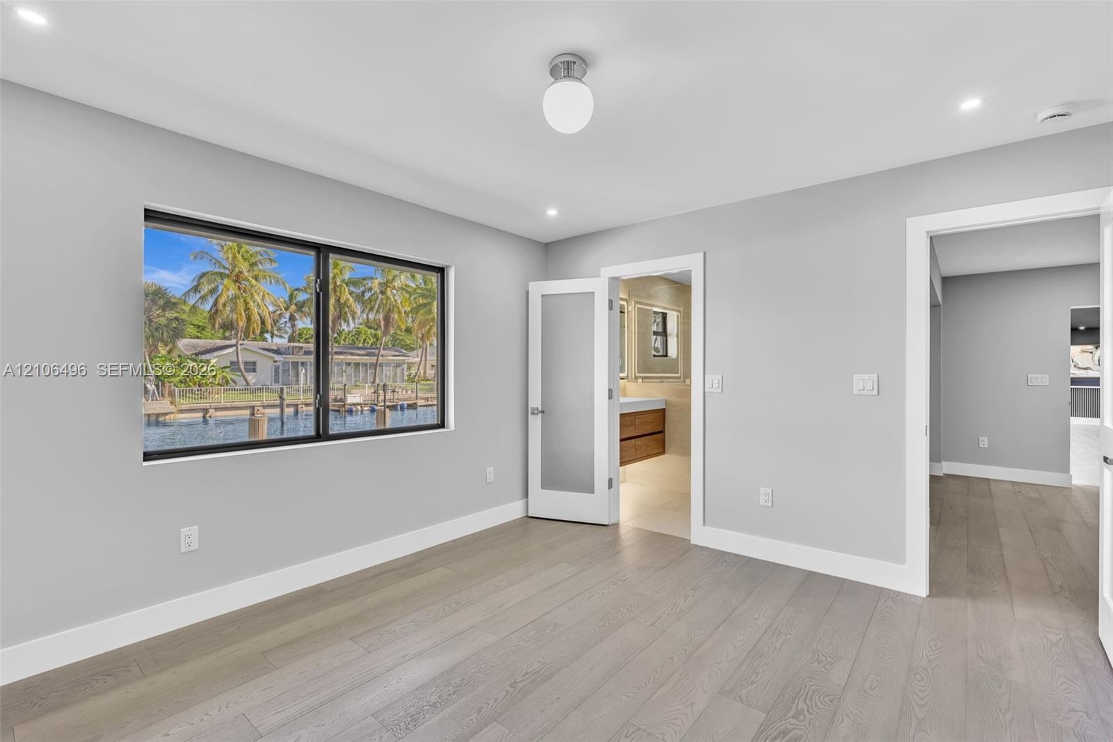 Interior space featuring wood-finish flooring, recessed lighting, a globe ceiling fixture, a large horizontal window with black trim, and a frosted gl