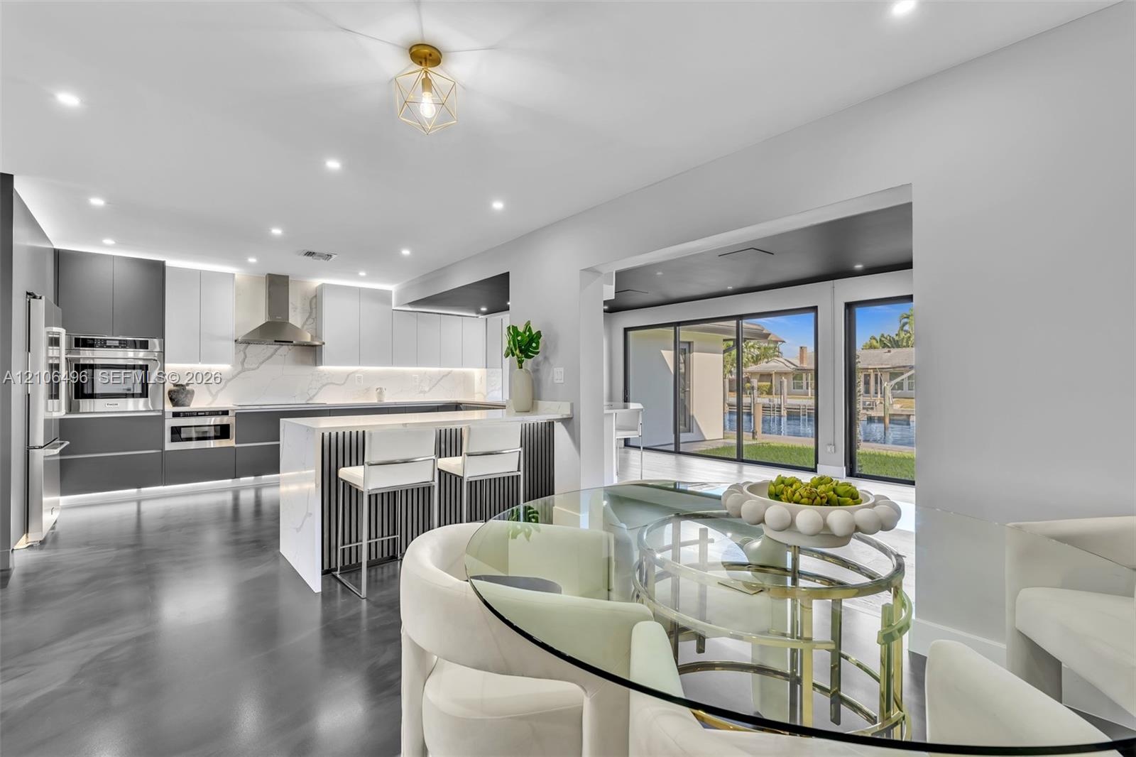 Contemporary kitchen featuring two-toned cabinetry, quartz countertops with full-height backsplash, stainless steel appliances, a tiered center island