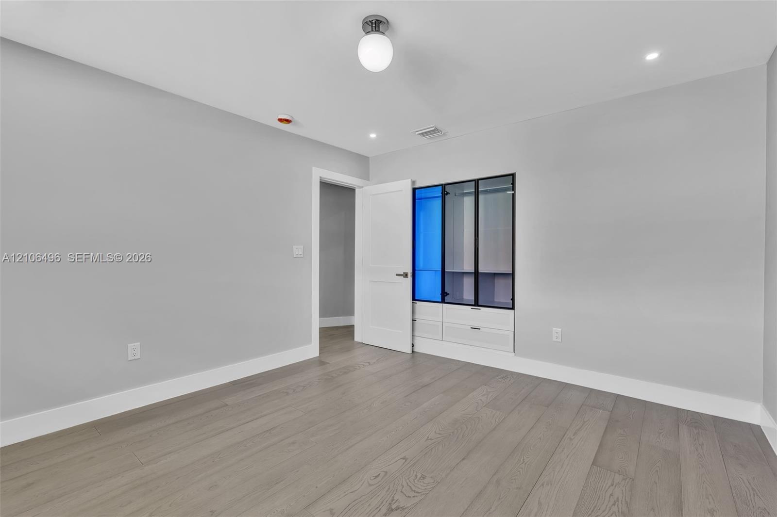 Wood-finish flooring, recessed lighting, and built-in cabinetry featuring glass-front doors and integrated drawers