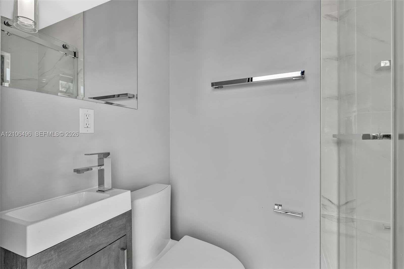 Modern bathroom featuring a wood-finish vanity, white rectangular vessel sink, polished chrome fixtures, wall-mounted mirror, and walk-in shower with 