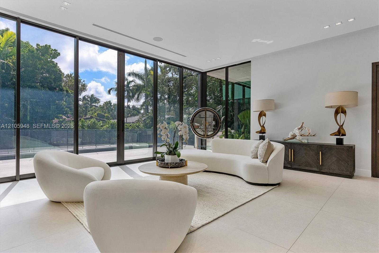 Floor-to-ceiling glass wall panels with dark metal framing, expansive polished tile flooring, and recessed ceiling lighting