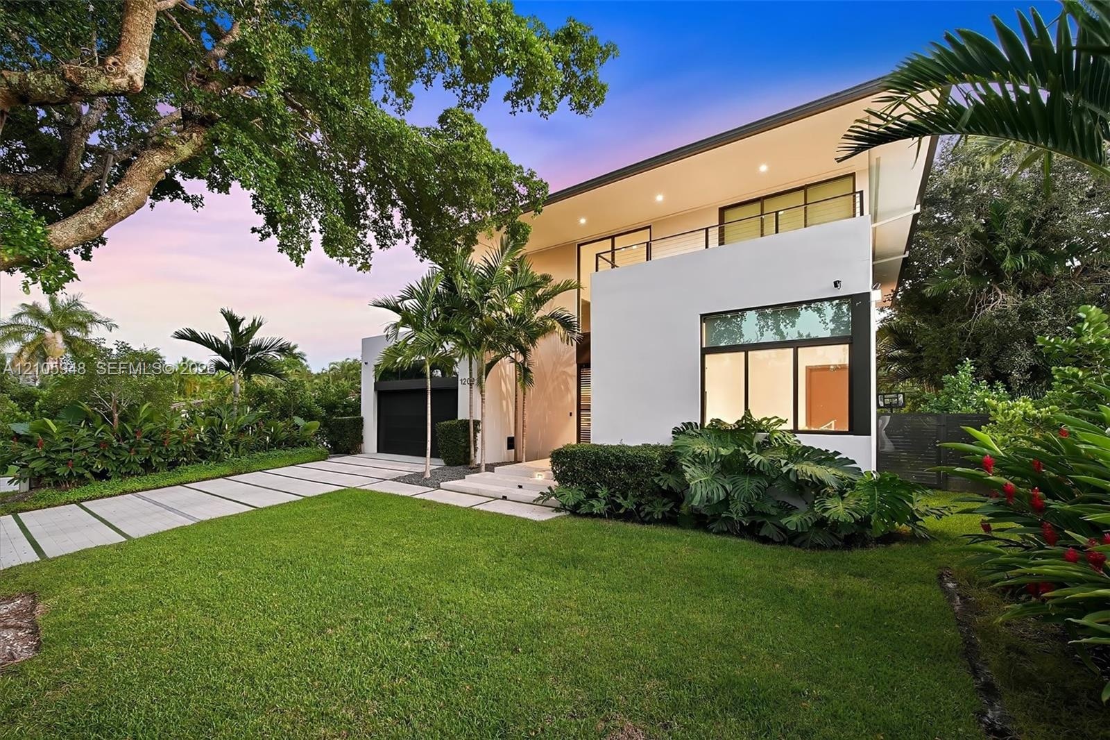 Modern architectural exterior featuring a smooth stucco facade, expansive floor-to-ceiling windows, a second-story cantilevered balcony with metal rai