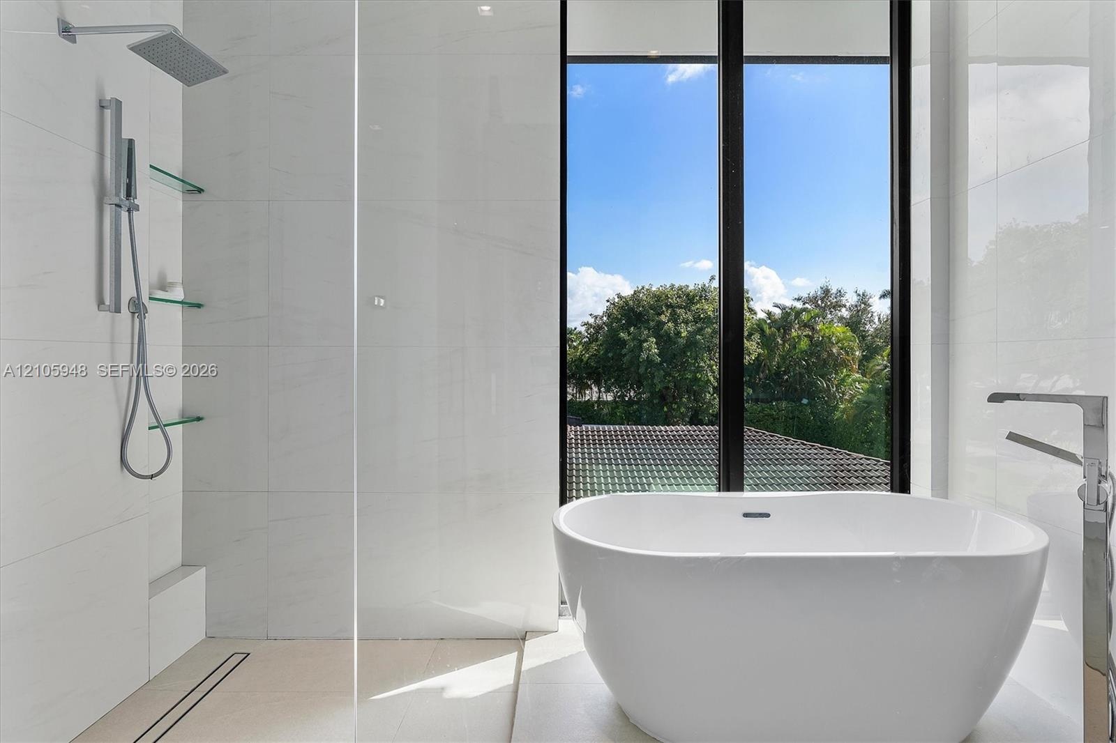 Freestanding soaking tub with floor-mounted faucet, walk-in shower with large-format tile surround, rainfall showerhead, and integrated glass shelving