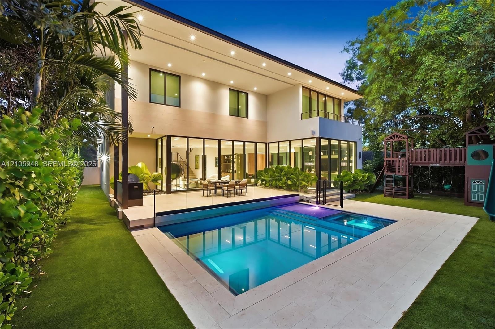 Contemporary multi-level exterior with floor-to-ceiling glass wall systems, paved stone patio, integrated swimming pool with built-in spa, and artific