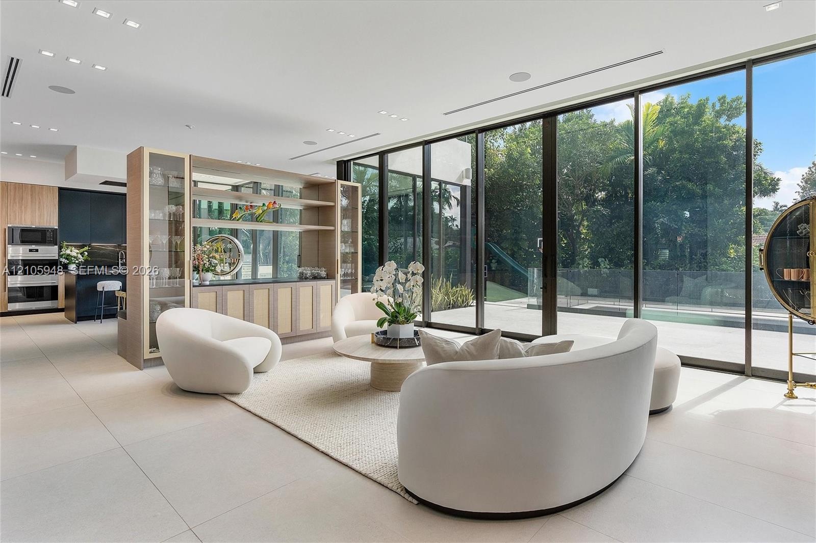 Floor-to-ceiling sliding glass doors, integrated custom shelving unit with glass-front cabinetry, large-format tile flooring, recessed lighting, and b