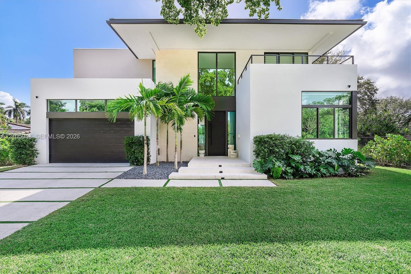 Modern architectural exterior featuring smooth stucco finish, geometric flat roofline, oversized floor-to-ceiling windows, second-story balcony with m