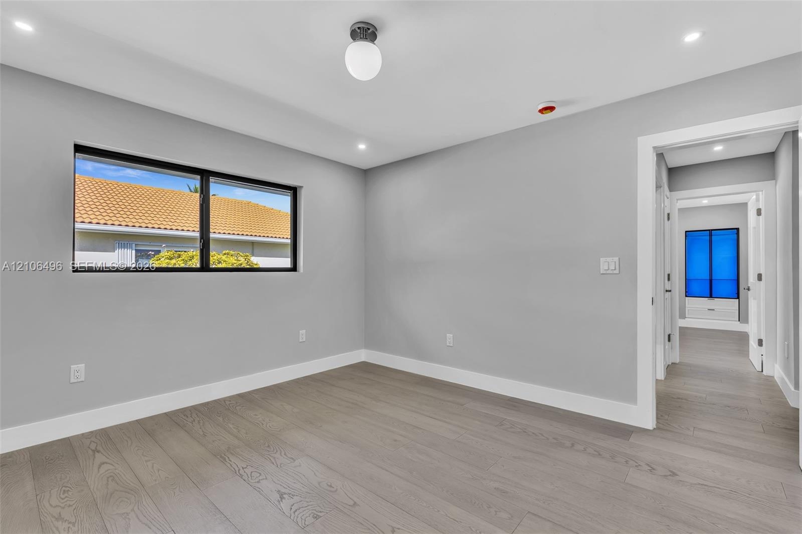 Neutral-toned walls, wood-finish flooring, recessed lighting, and a window with a black frame