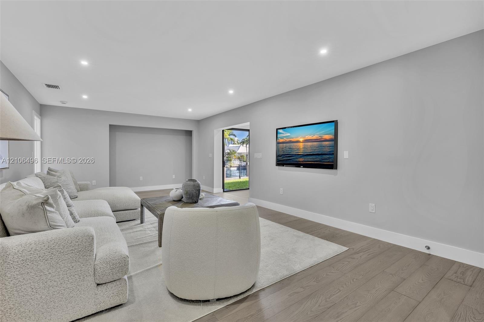 Living area featuring recessed lighting, neutral wall paint, wood-finish flooring, and a recessed wall niche