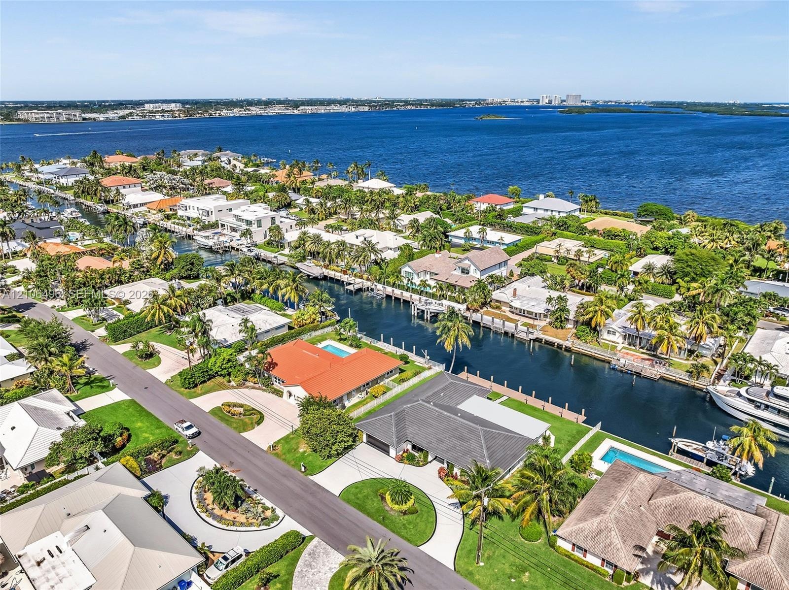 Aerial perspective of a coastal neighborhood featuring deep-water canal access, private boat docks, residential swimming pools, mature palm landscapin