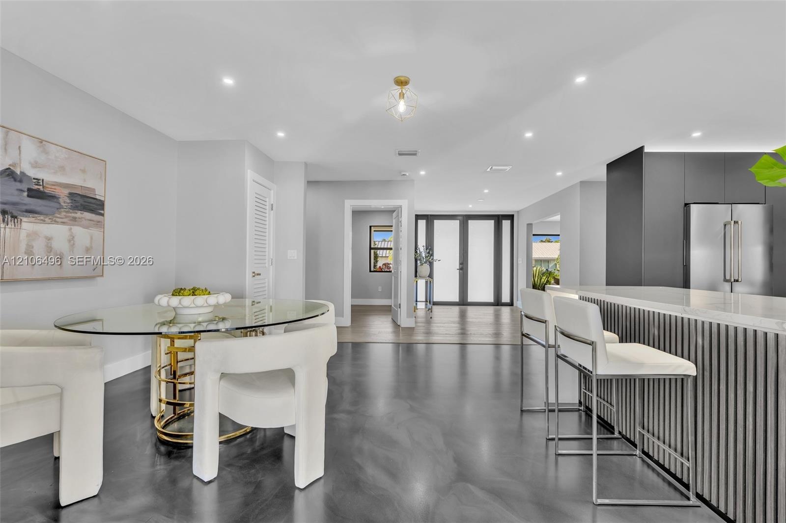 Open-concept interior featuring high-gloss polished flooring, recessed lighting, a modern kitchen island with vertical slat detailing, and a multi-pan