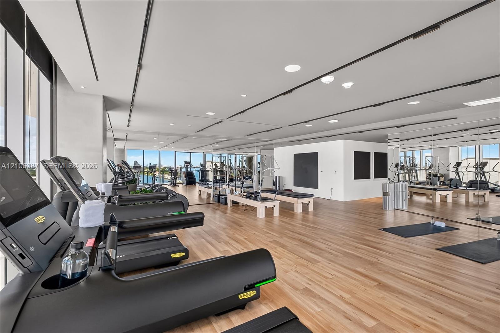 Fitness center featuring floor-to-ceiling windows, wood-finish flooring, full-wall mirrors, and recessed ceiling lighting