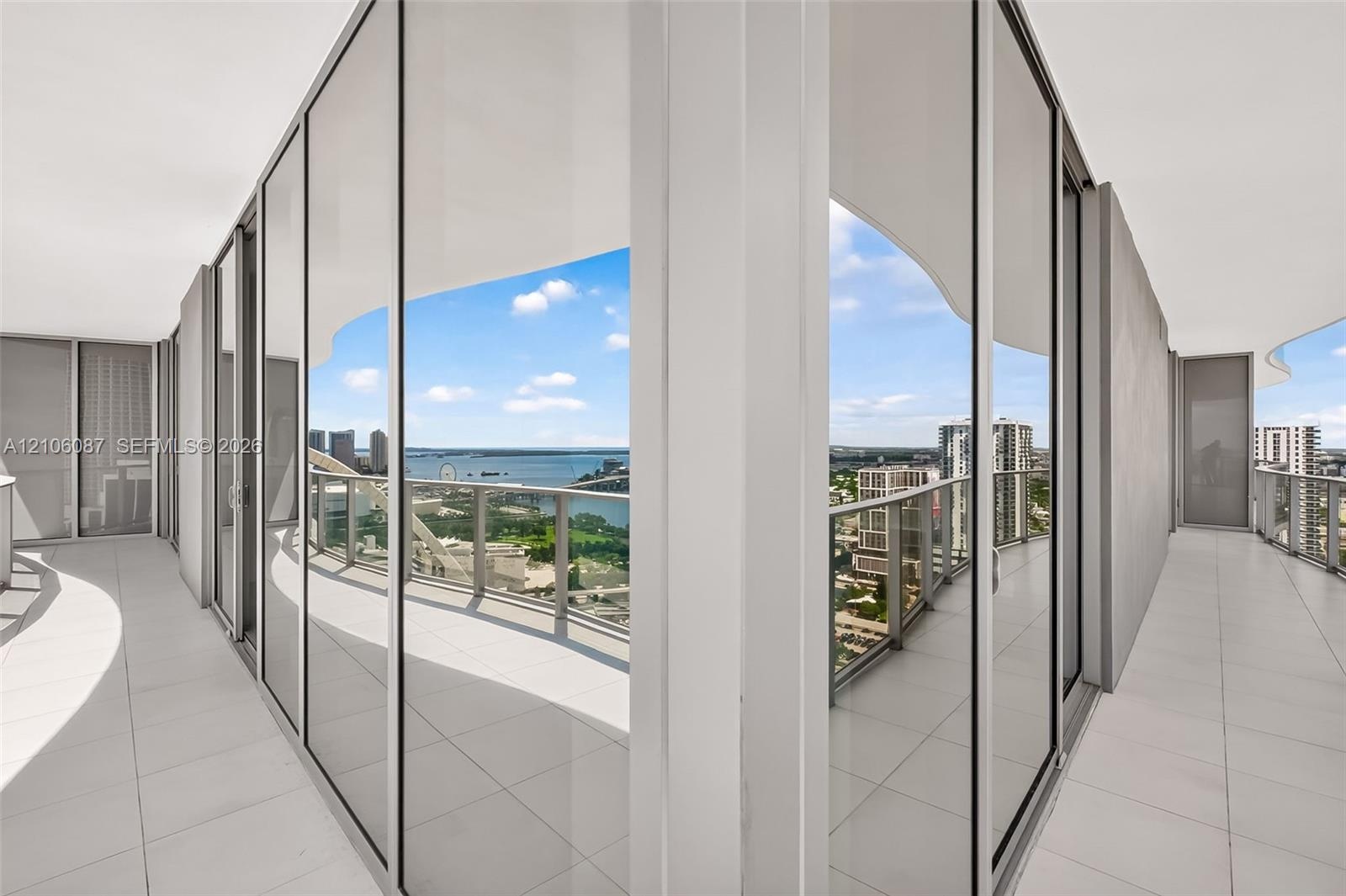 Wrap-around terrace featuring floor-to-ceiling glass walls, sleek metal railings, and tile flooring