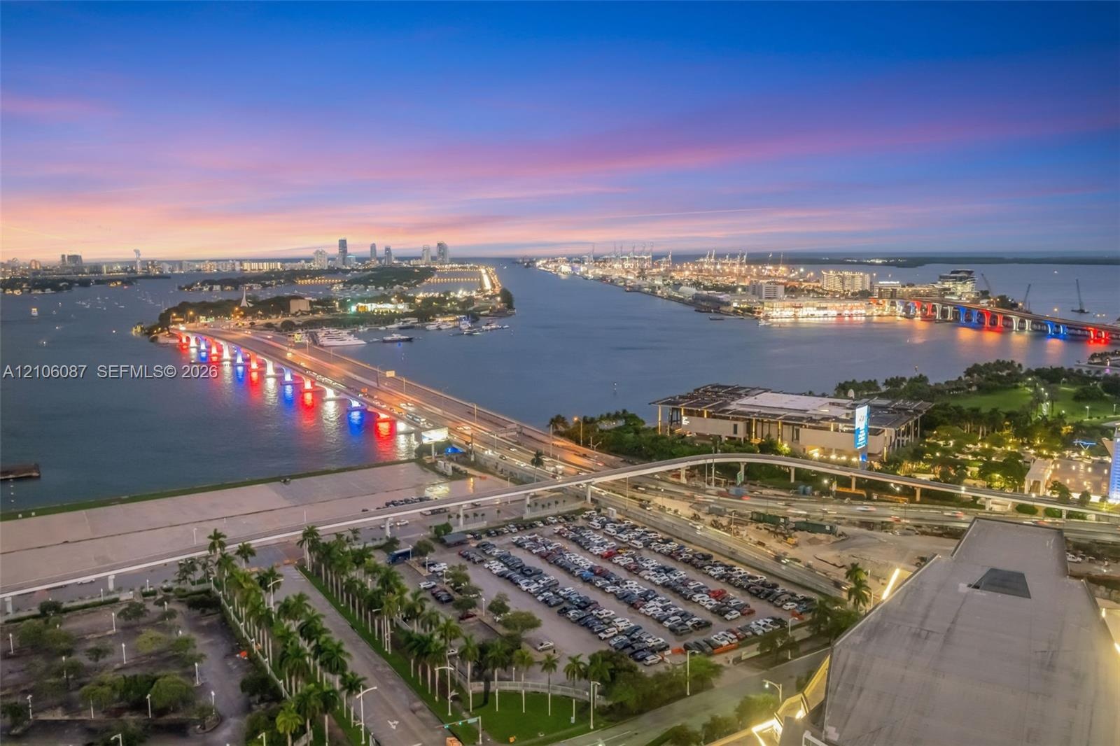Aerial perspective featuring a waterfront coastline, bridge infrastructure, city skyline, and surrounding harbor