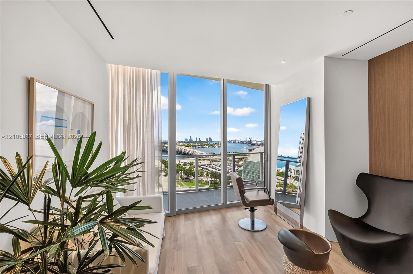 Floor-to-ceiling glass windows, wood-finish flooring, recessed lighting, and a private balcony featuring a metal railing