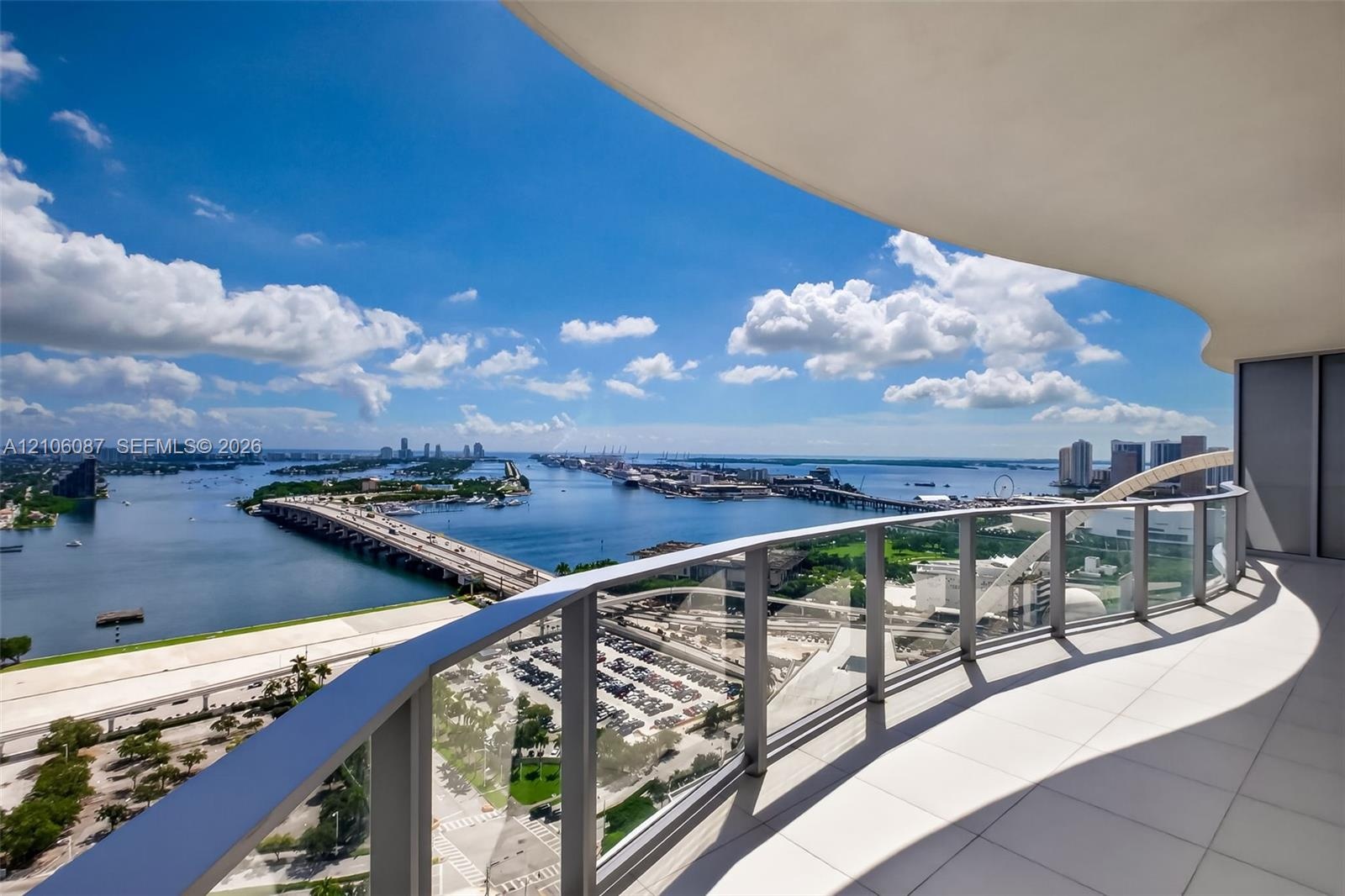 Curved balcony featuring large-format tile flooring and a glass-paneled railing with metal framing