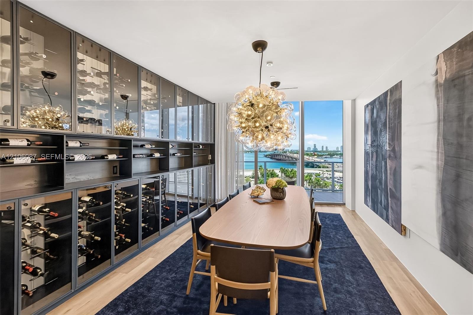 Custom floor-to-ceiling glass-front wine cabinetry, expansive floor-to-ceiling windows, spherical multi-bulb pendant lighting, and light-toned wood-fi