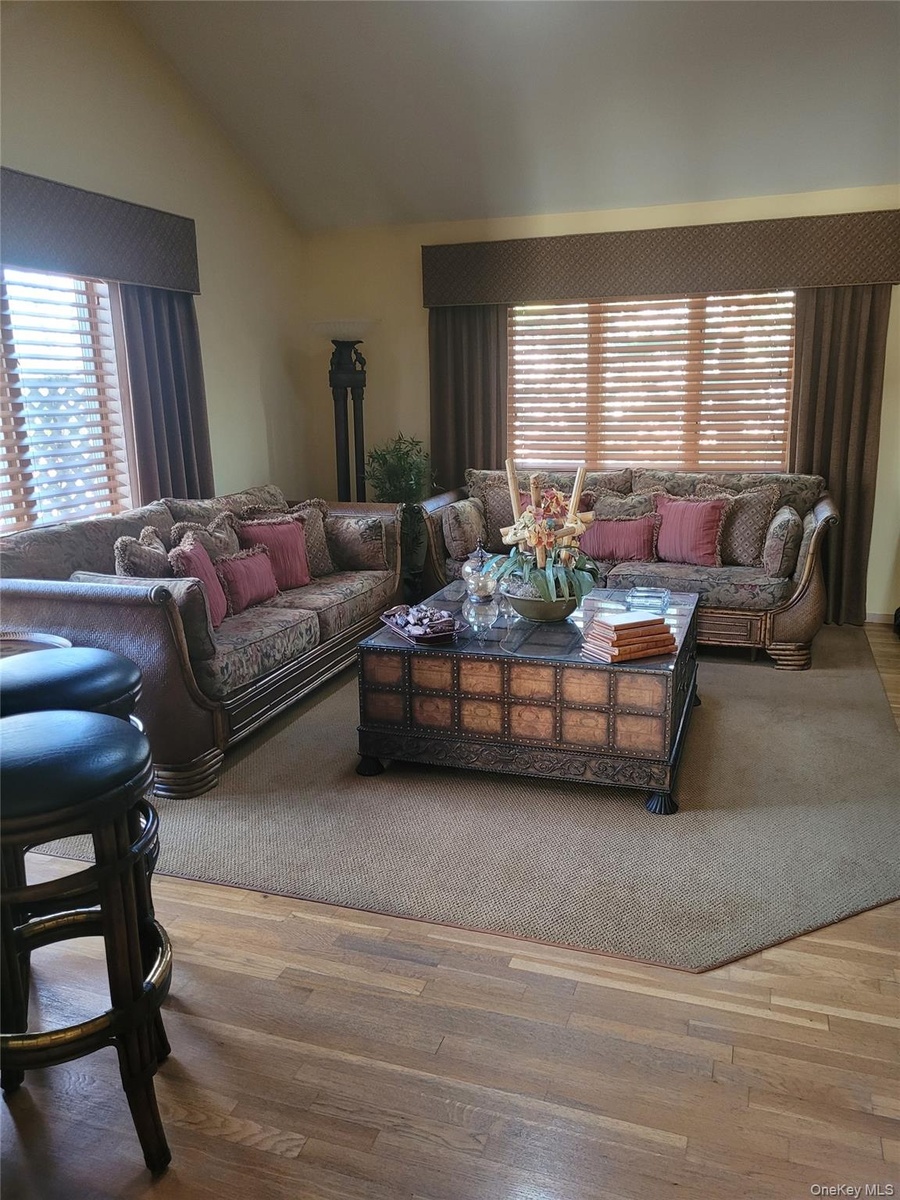 Vaulted ceiling, wood-finish flooring, and multiple window treatments