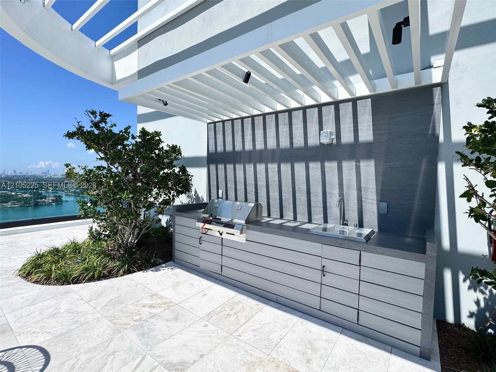 Outdoor kitchen featuring a built-in grill, integrated sink, and cabinetry