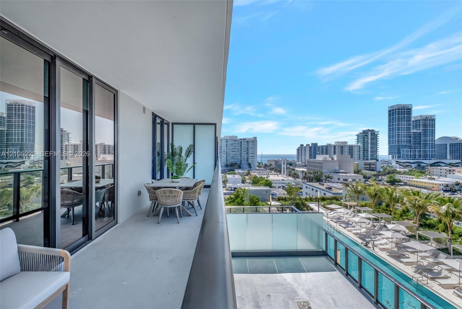 Covered terrace featuring floor-to-ceiling glass sliding doors, dark metal railings, and concrete flooring
