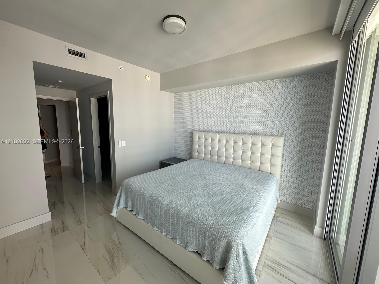 Large-format stone-finish flooring and geometric patterned accent wall featuring a recessed alcove